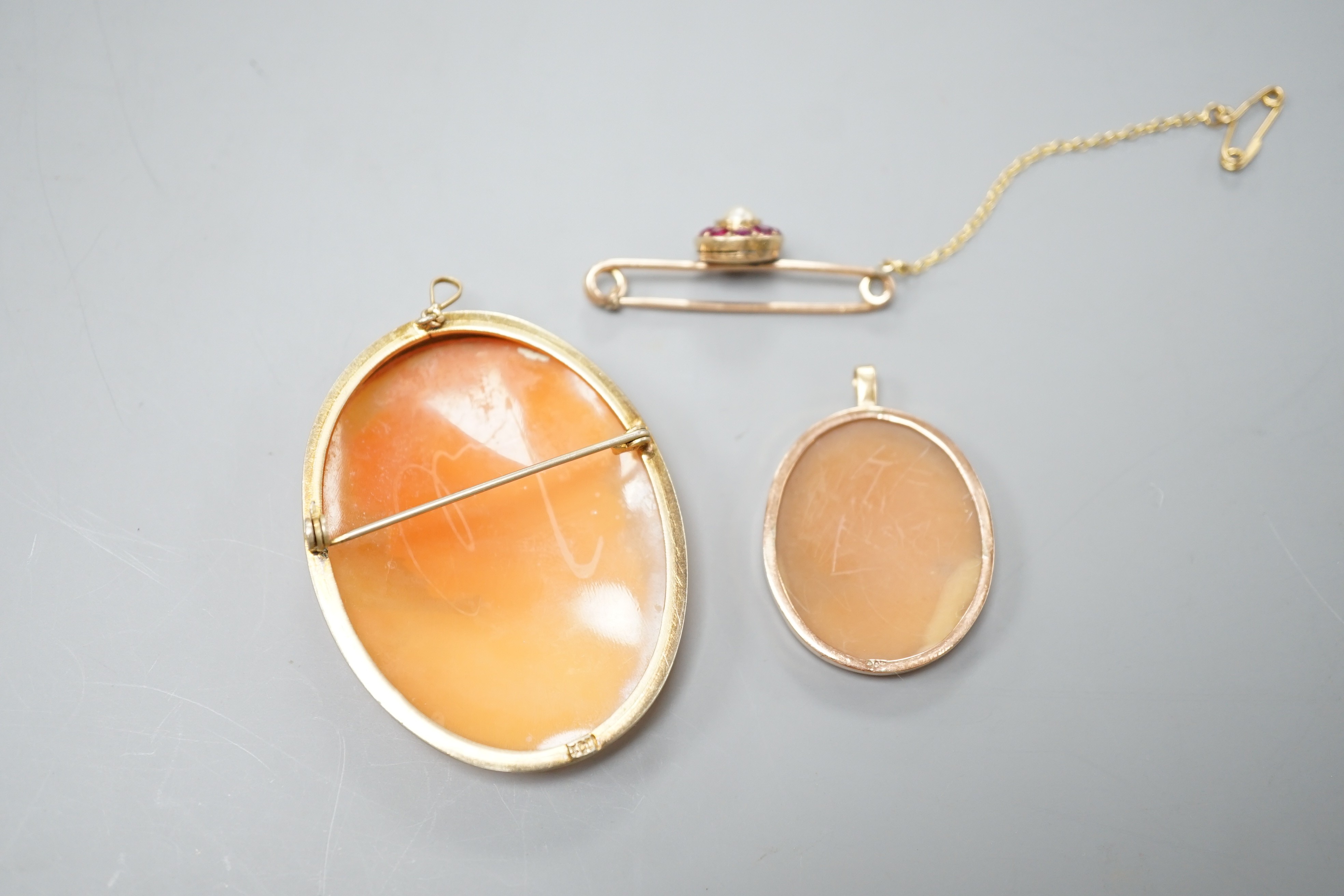 A 9ct mounted oval cameo shell pendant, 36mm, a similar gilt white metal mounted brooch and a yellow metal, ruby and cultured pearl cluster set bar brooch(converted).